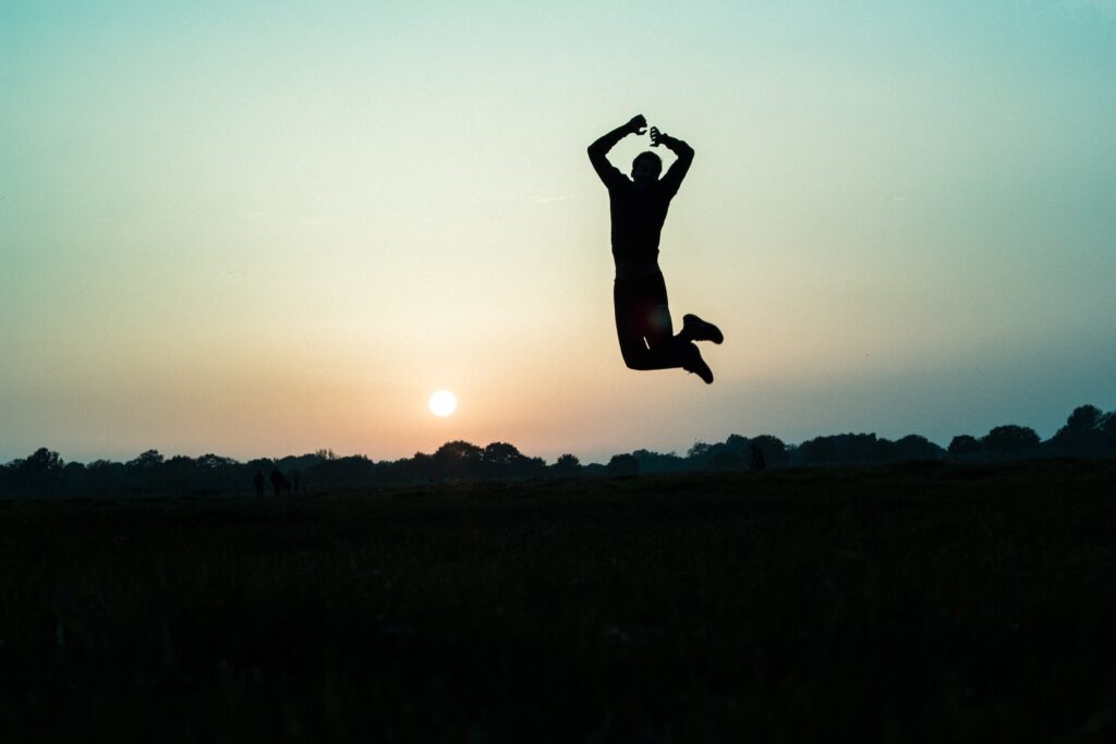 男性が大自然の中でジャンプしている写真